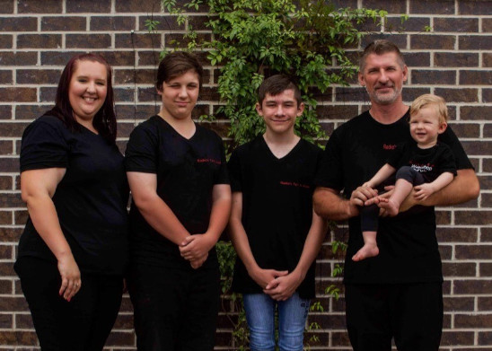 Photo of the Radke family, parents and three kids, standing against a brick wall