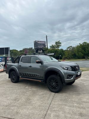  Grey Nissan Navara Warrior edition with black aftermarket wheels and lifted suspension.