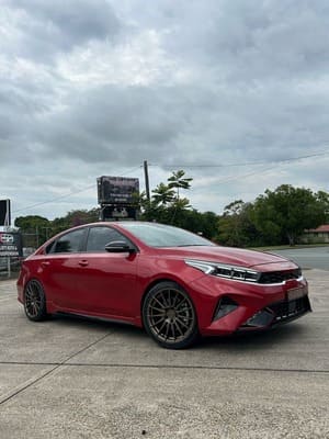  Red Kia Cerato sedan lowered on bronze aftermarket alloy wheels.