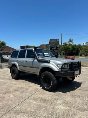  Silver Toyota LandCruiser 80 Series with snorkel, bull bar, black steel wheels and mud-terrain tyres.