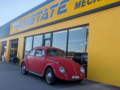 Classic red Volkswagen Beetle parked outside the Transtate workshop 