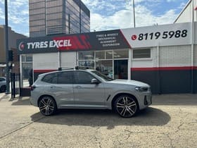  Silver BMW X3 with custom black alloy wheels parked outside Tyres Excel workshop.