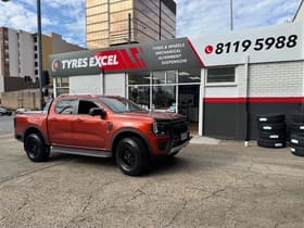  Orange Ford Ranger Raptor with off-road tyres and black wheels outside Tyres Excel.