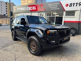  Black Toyota LandCruiser 300 Series with bronze off-road wheels outside Tyres Excel.